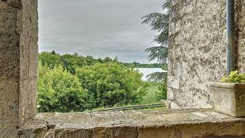 A stone window with a view of a lake and trees.