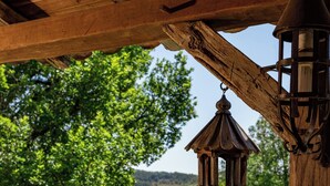 Une pergola en bois, ornée d’une lanterne suspendue, et offrant une vue sur un paysage verdoyant luxuriant.