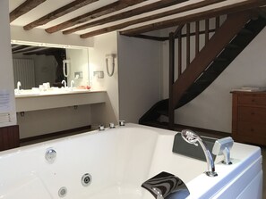 Ein modernes Badezimmer mit einer großen Badewanne, einer Holztreppe und einem Waschtisch mit Spiegel.