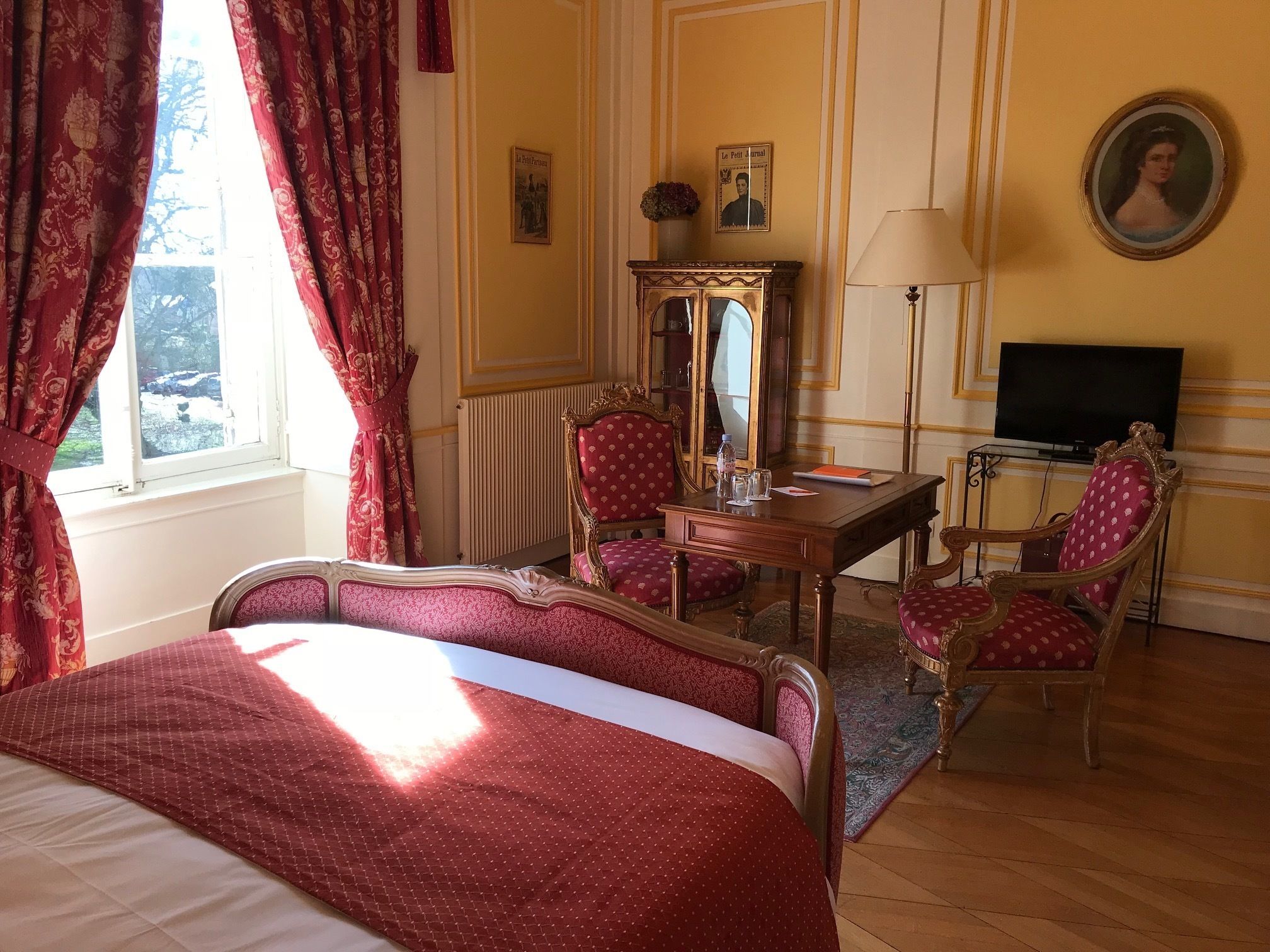 Une chambre d’hôtel équipée d’un lit, d’un bureau, d’une chaise, d’un miroir et d’une télévision.