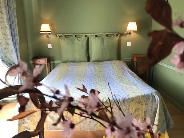 Une chambre à coucher avec un lit, deux lampes de chevet, une table de chevet et une fenêtre avec des rideaux.