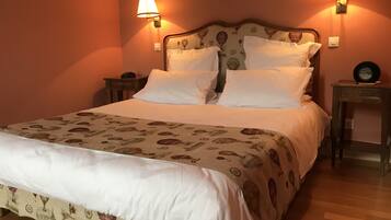 A neatly made bed with a patterned bedspread, two bedside lamps, and a small table with a clock.