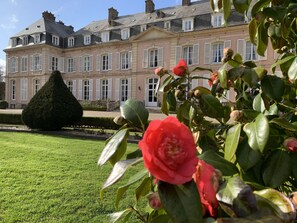 Un grand bâtiment historique à l’architecture symétrique, doté d’une pelouse bien entretenue et d’un remarquable jardin à la française.