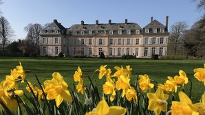Een groot, historisch gebouw met een symmetrische gevel en meerdere schoorstenen.