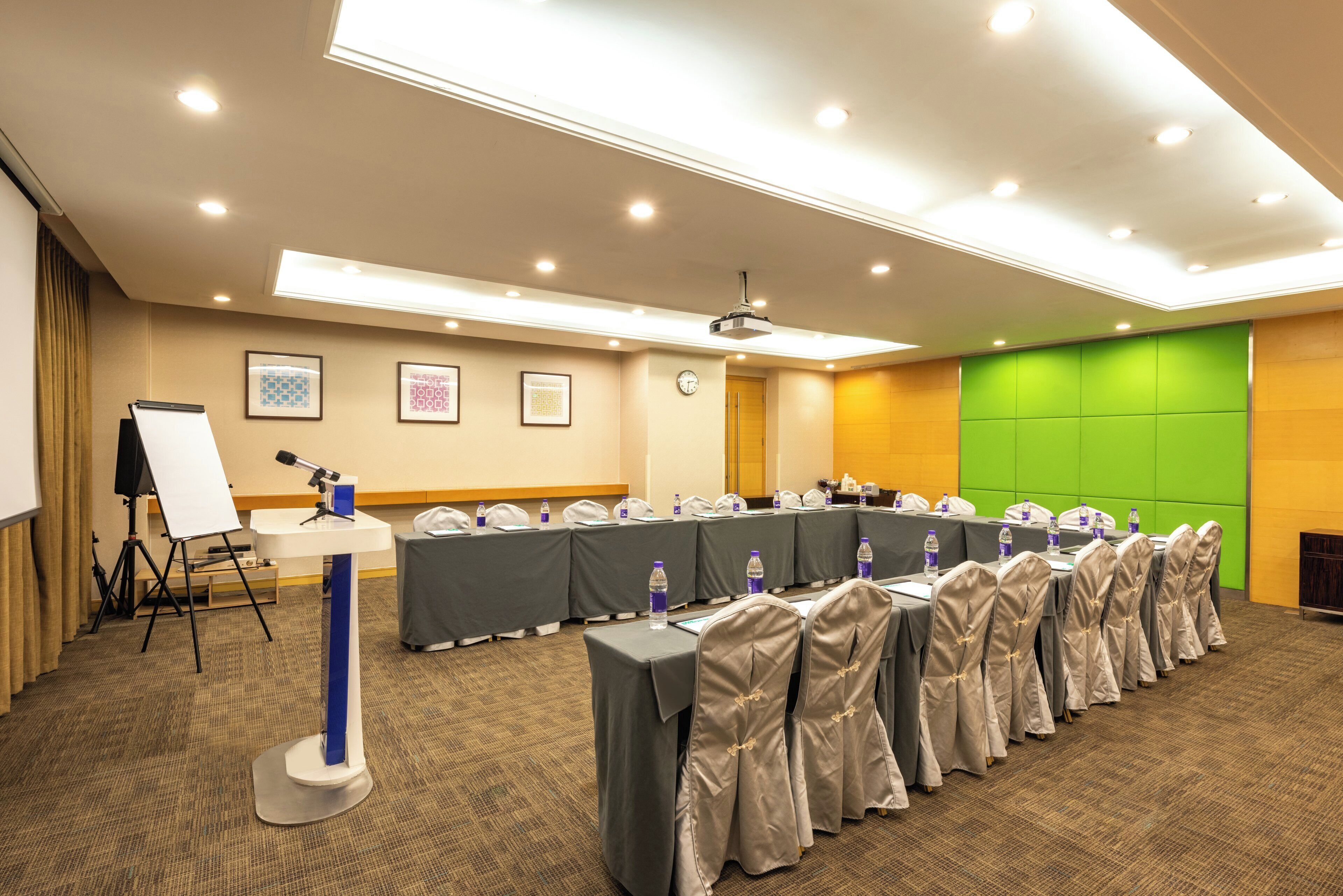 A conference room with a long table, chairs, a whiteboard, and a projector.