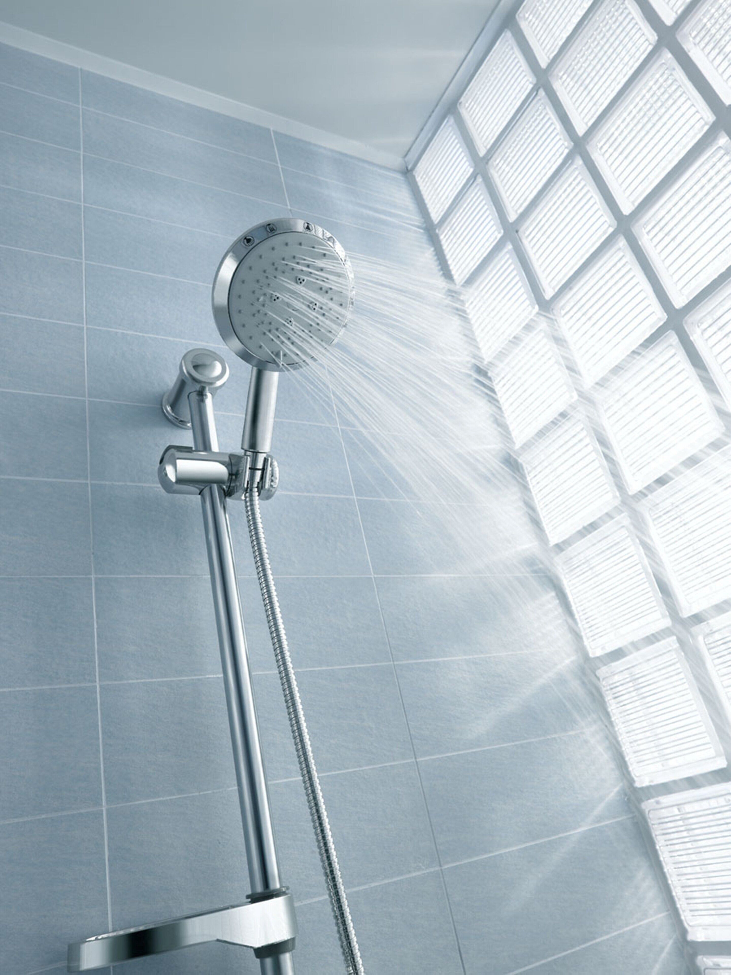 Un cabezal de ducha con agua corriente, sujeto a una pared con diseño de cuadrícula.
