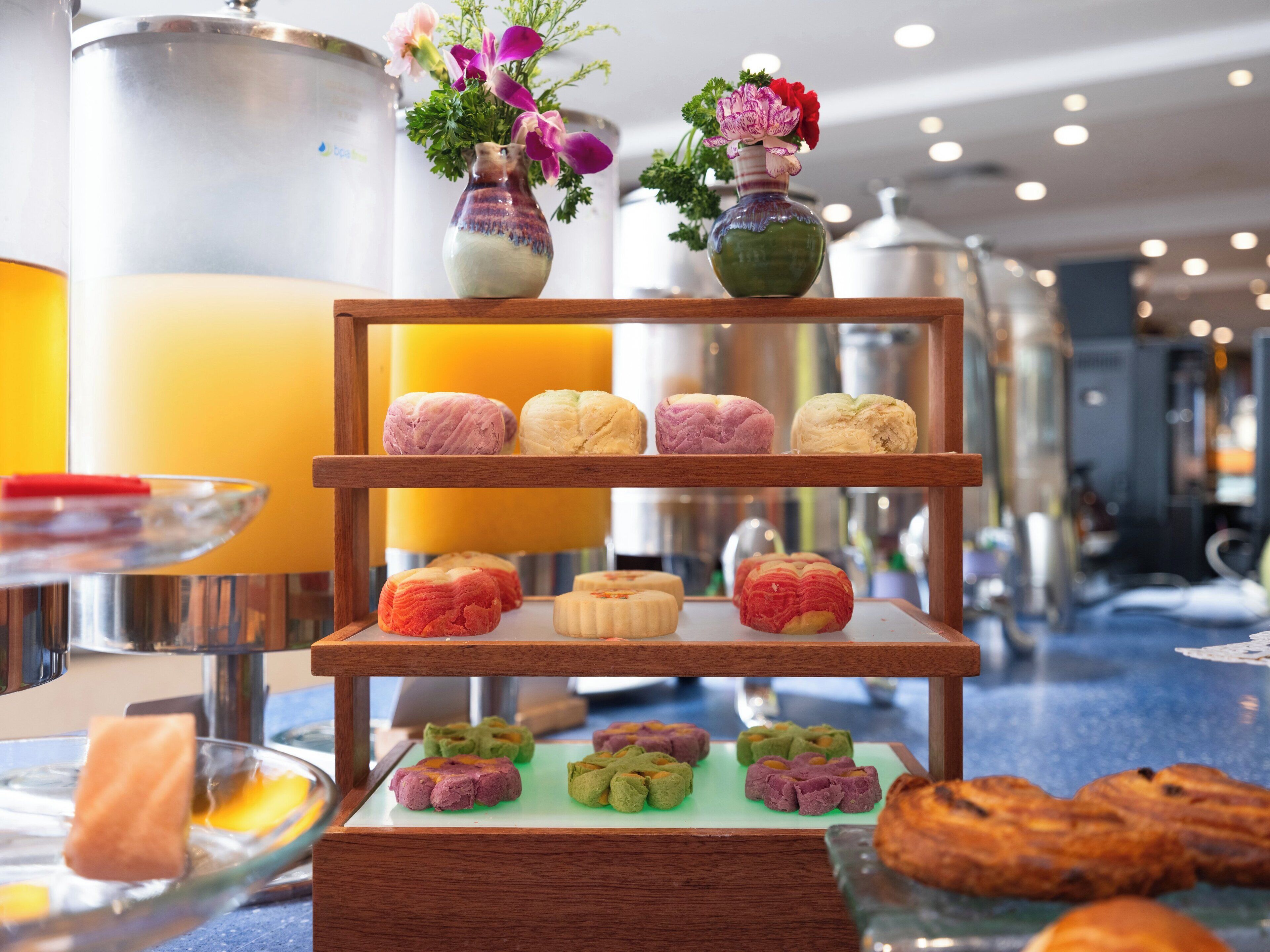 A buffet with various pastries and a vase with flowers.