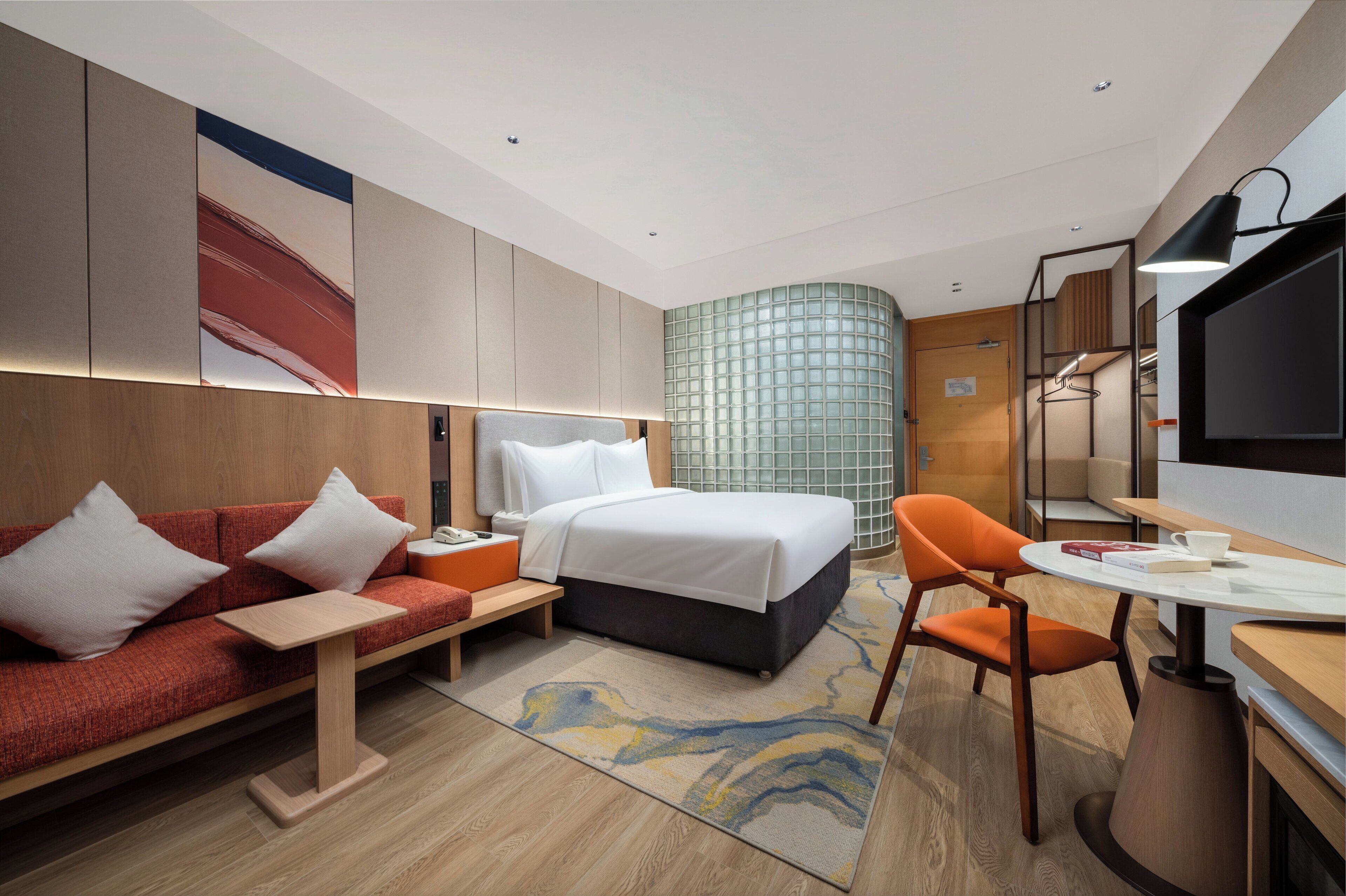 Una habitación de hotel moderna con una cama, un sofá, un escritorio y un televisor.