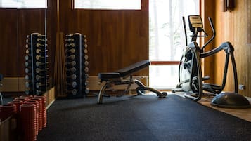A gym with a bench, weight racks, and exercise equipment.