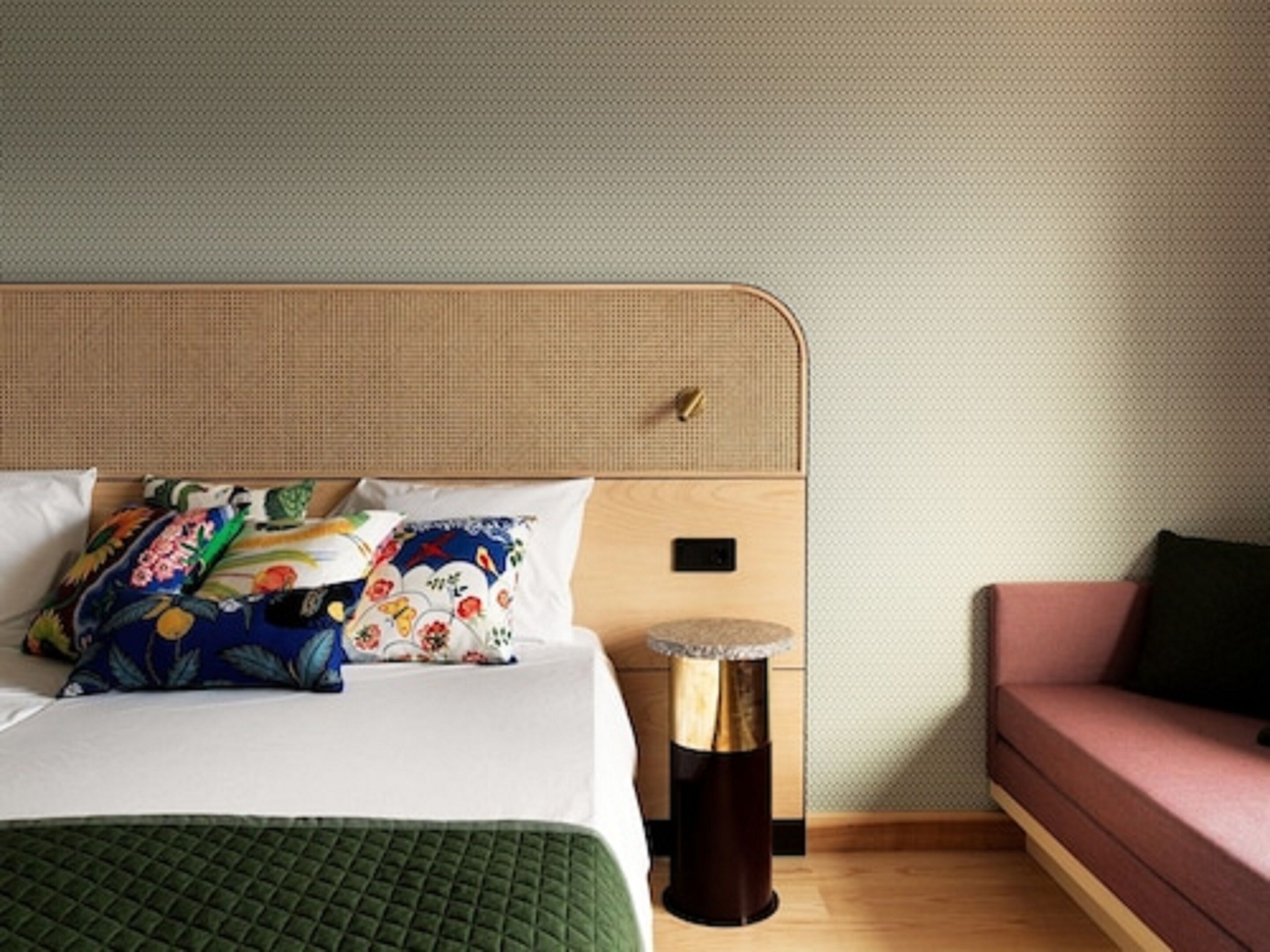 Una habitación de hotel con una cama, una mesita de noche, una lámpara y un sofá.