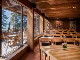 Un restaurante con amplios ventanales, mesas y sillas de madera.