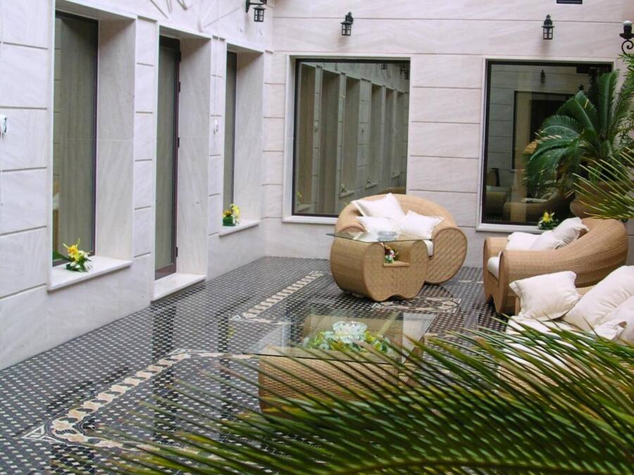 A modern indoor courtyard with a tiled floor, wicker furniture, and potted plants.