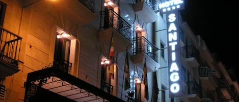A hotel with a prominent sign reading "HOTEL SANTIAGO" and a balcony with railings.