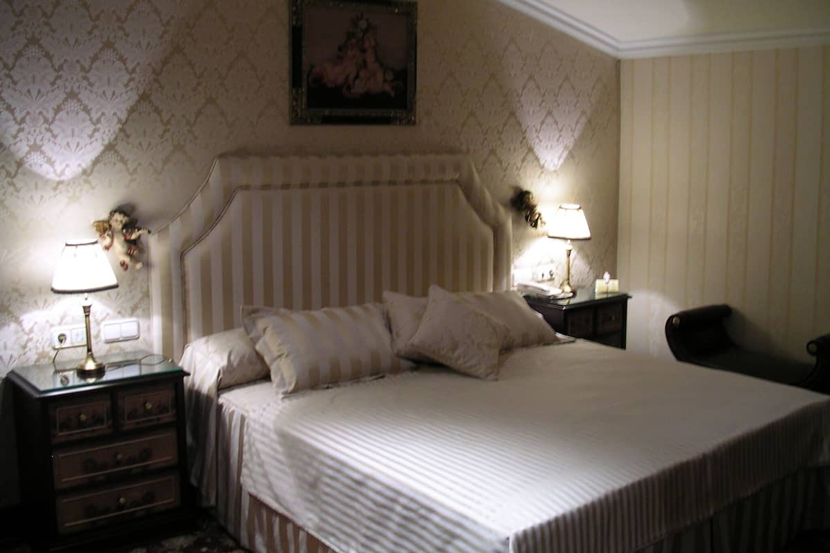 A neatly made bed with a striped headboard, two bedside tables with lamps, and a framed picture on the wall.