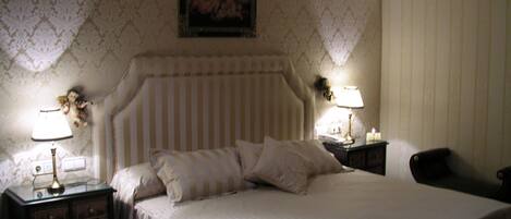 A neatly made bed with a striped headboard, two bedside tables with lamps, and a framed picture on the wall.