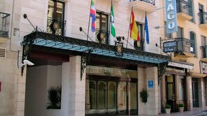 Een hotelgevel in klassieke stijl, met een opvallende ingang met glazen deuren en een metalen luifel.