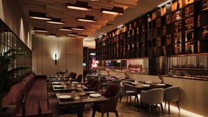 A modern restaurant interior with a long counter, multiple dining tables, and chairs.