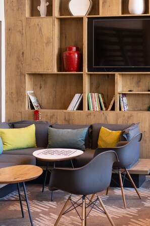 Un salon moderne avec un canapé d’angle, une table basse et un téléviseur à écran plat fixé sur un mur en bois.