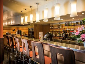 A bar area with a counter, stools, and a variety of bottles and glasses on shelves. - ibis Cannes Mandelieu (Mandelieu-La-Napoule)