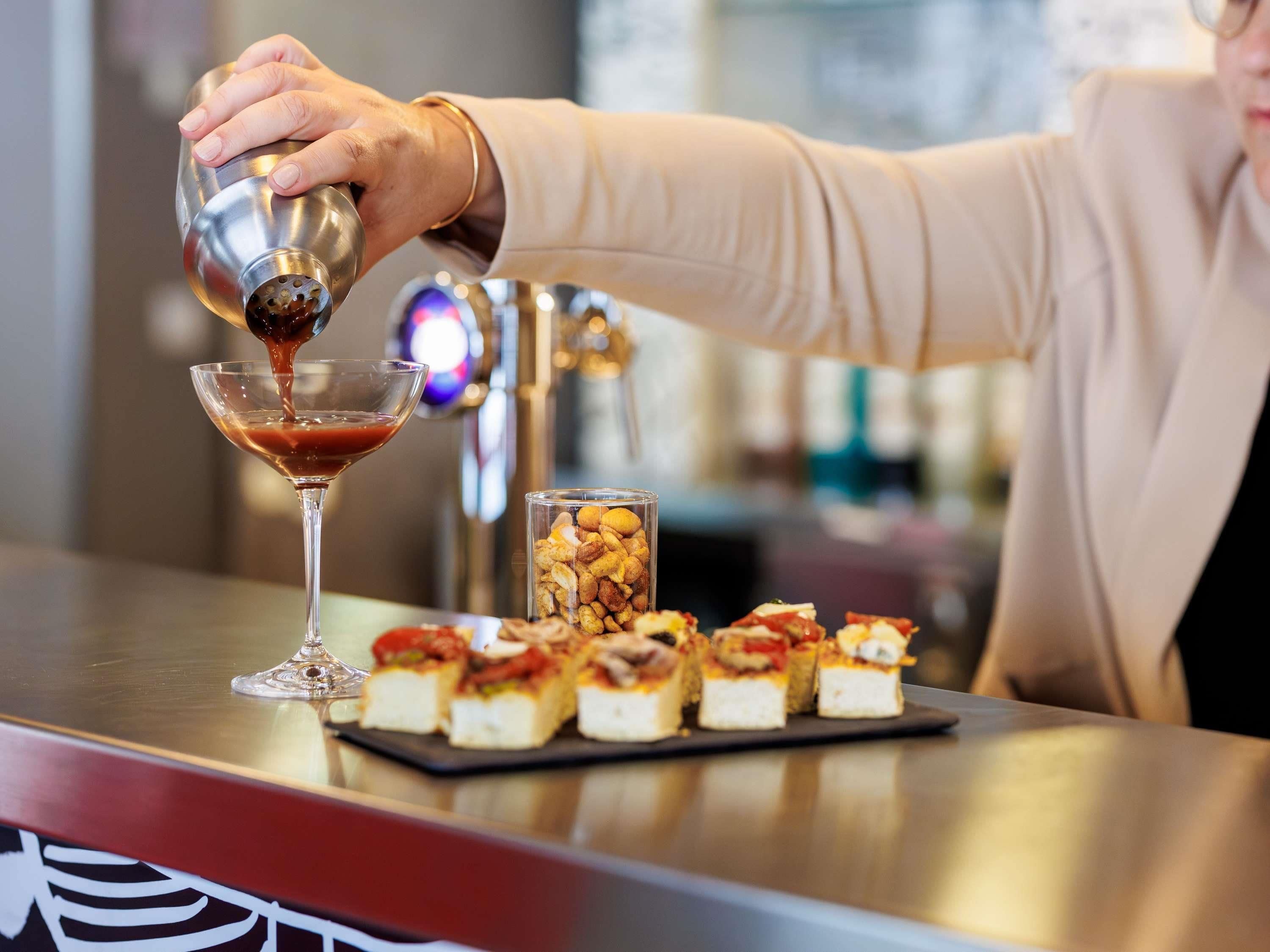 A bartender pouring a drink into a martini glass.