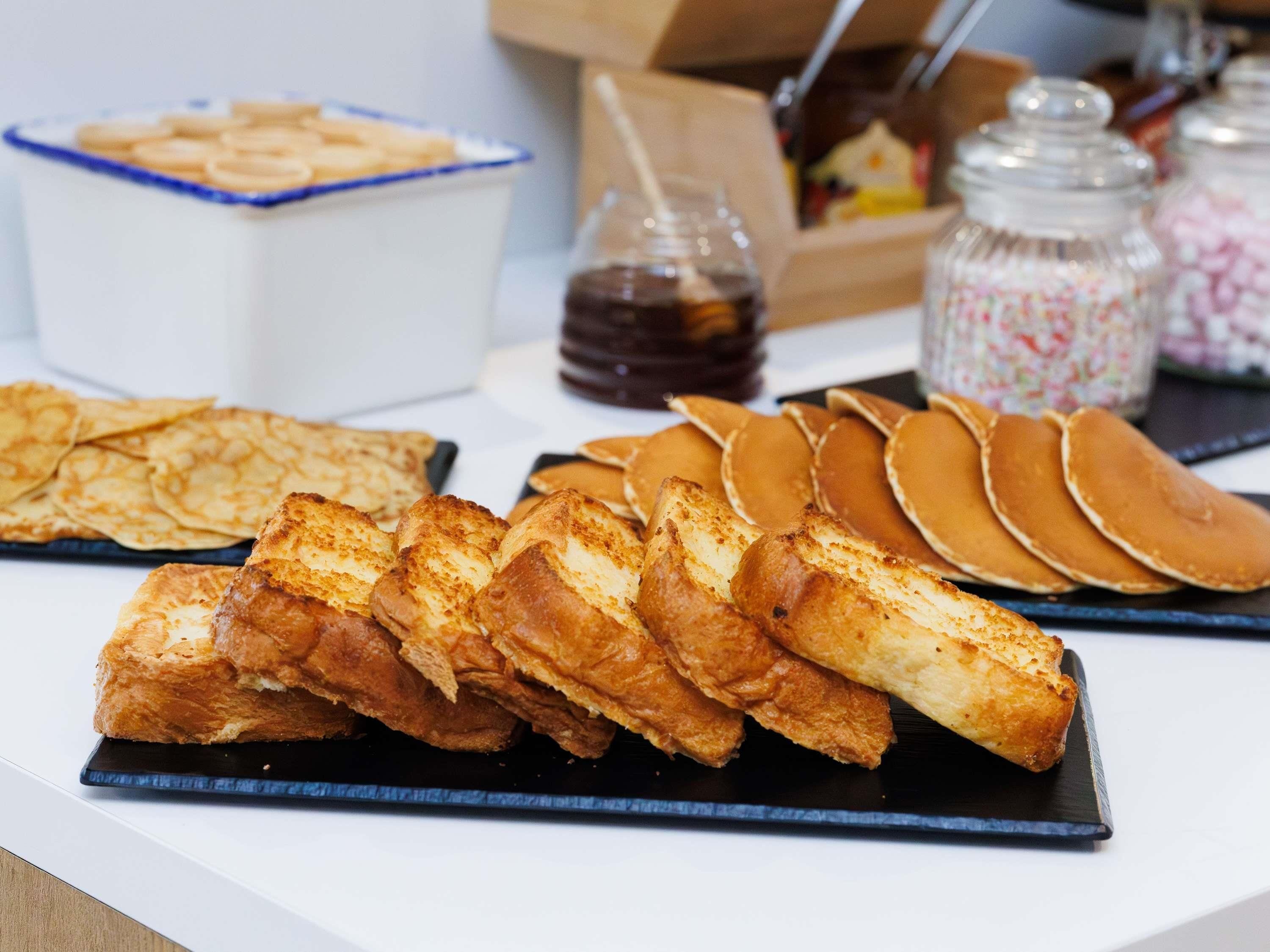 Een ontbijtbuffet met diverse gebakjes, pannenkoeken en toevoegingen.