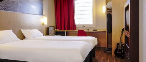 A hotel room with two beds, a desk, a chair, a guitar, and a window with red curtains.