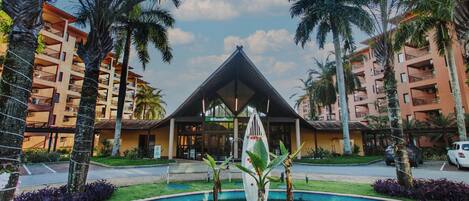 Ein Hotel mit Pool, Palmen und einem Gebäude mit Balkonen.