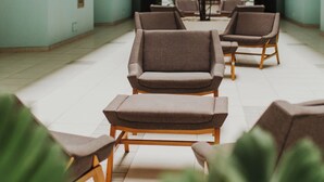 A spacious lobby with a high ceiling, multiple seating areas, and a central plant.