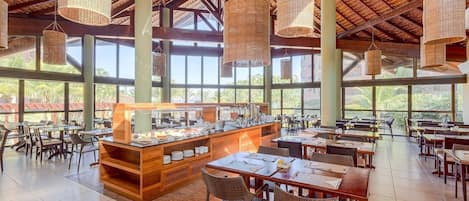 A spacious dining area with high ceilings, large windows, and a buffet counter.