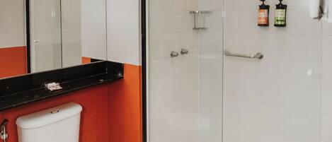 A bathroom with a toilet, a glass-enclosed shower, and a mirror.