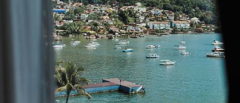 A view of a swimming pool with a view of a town and boats on the water.