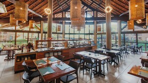 A spacious restaurant with high ceilings, large windows, and wicker hanging lights.