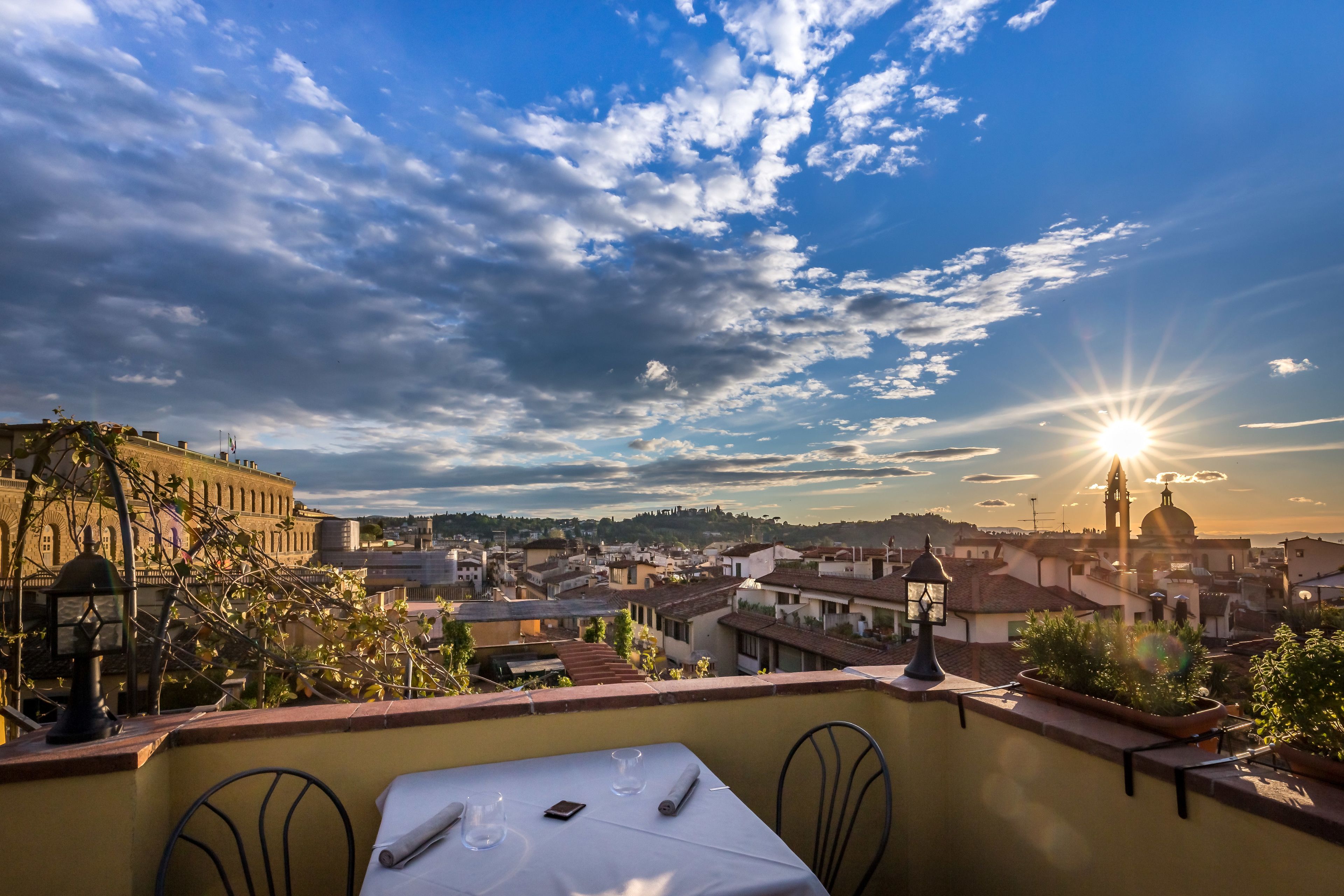 Eine Terrasse mit Tisch für zwei Personen, mit Blick auf eine historische Stadt und einem markanten Gebäude im Hintergrund.