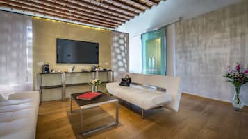 A modern living room with a sofa, coffee table, and a flat-screen TV mounted on the wall.