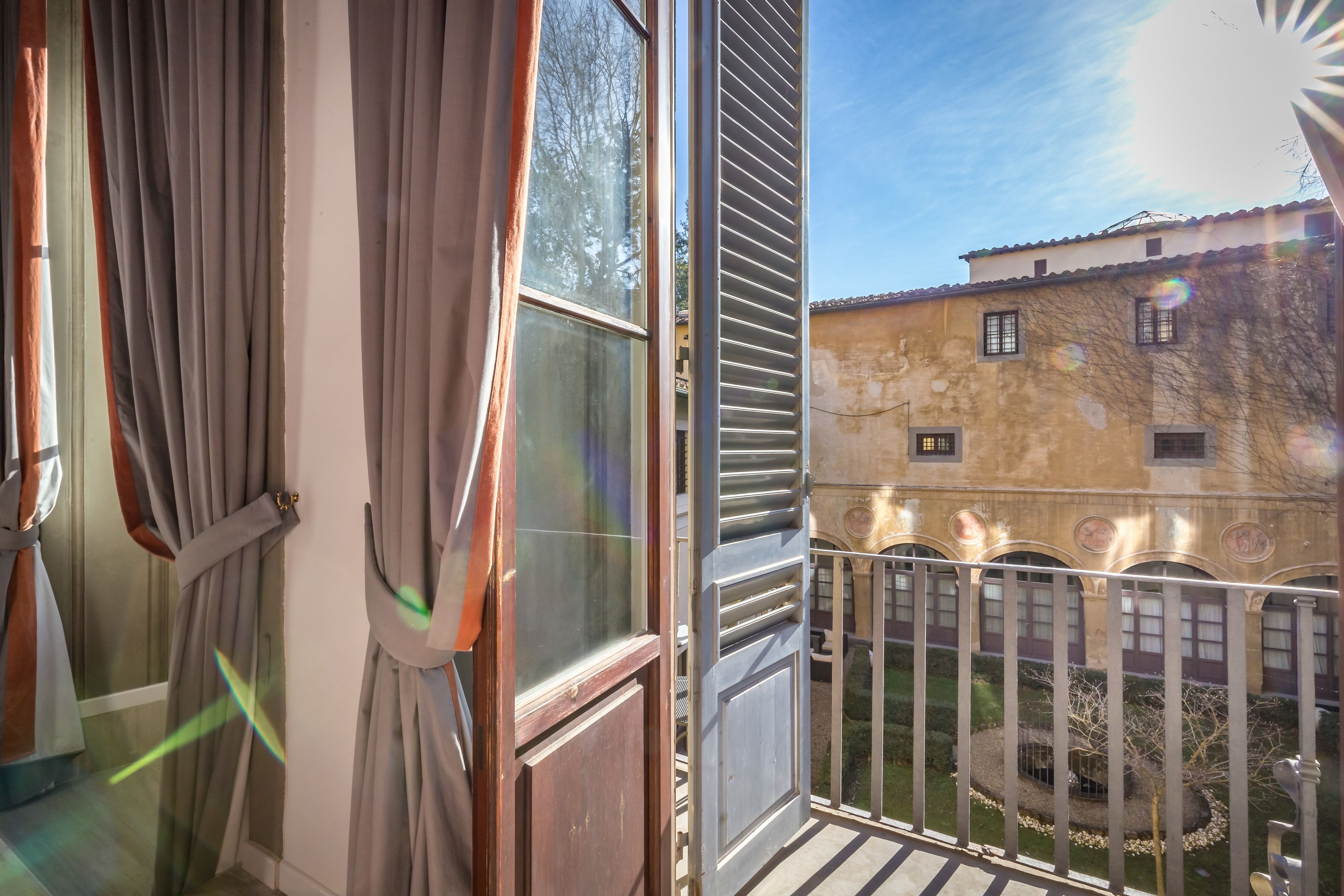 A balcony with a view of a building with a tiled roof and a circular window.