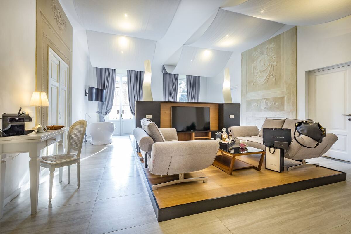A modern living room with a sofa, chairs, a coffee table, a TV, and a dining area with a table and chairs.
