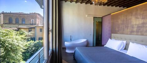 Un dormitorio moderno con una cama grande, una bañera blanca y vistas a un paisaje urbano.