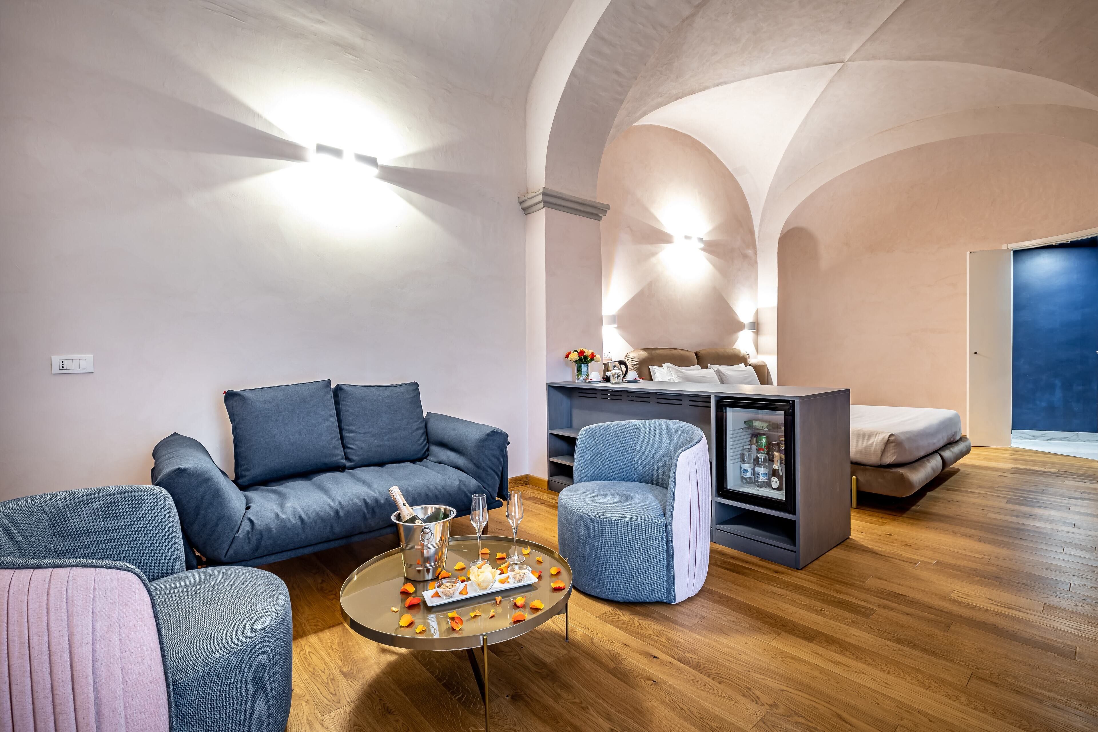 Ein modernes Wohnzimmer mit einem blauen Sofa, einem runden Couchtisch mit Snacks und einem grauen Sessel.