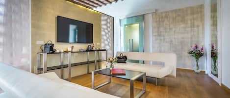 Una sala de estar moderna con un sofá blanco, una mesa de centro de vidrio y un televisor instalado en la pared.