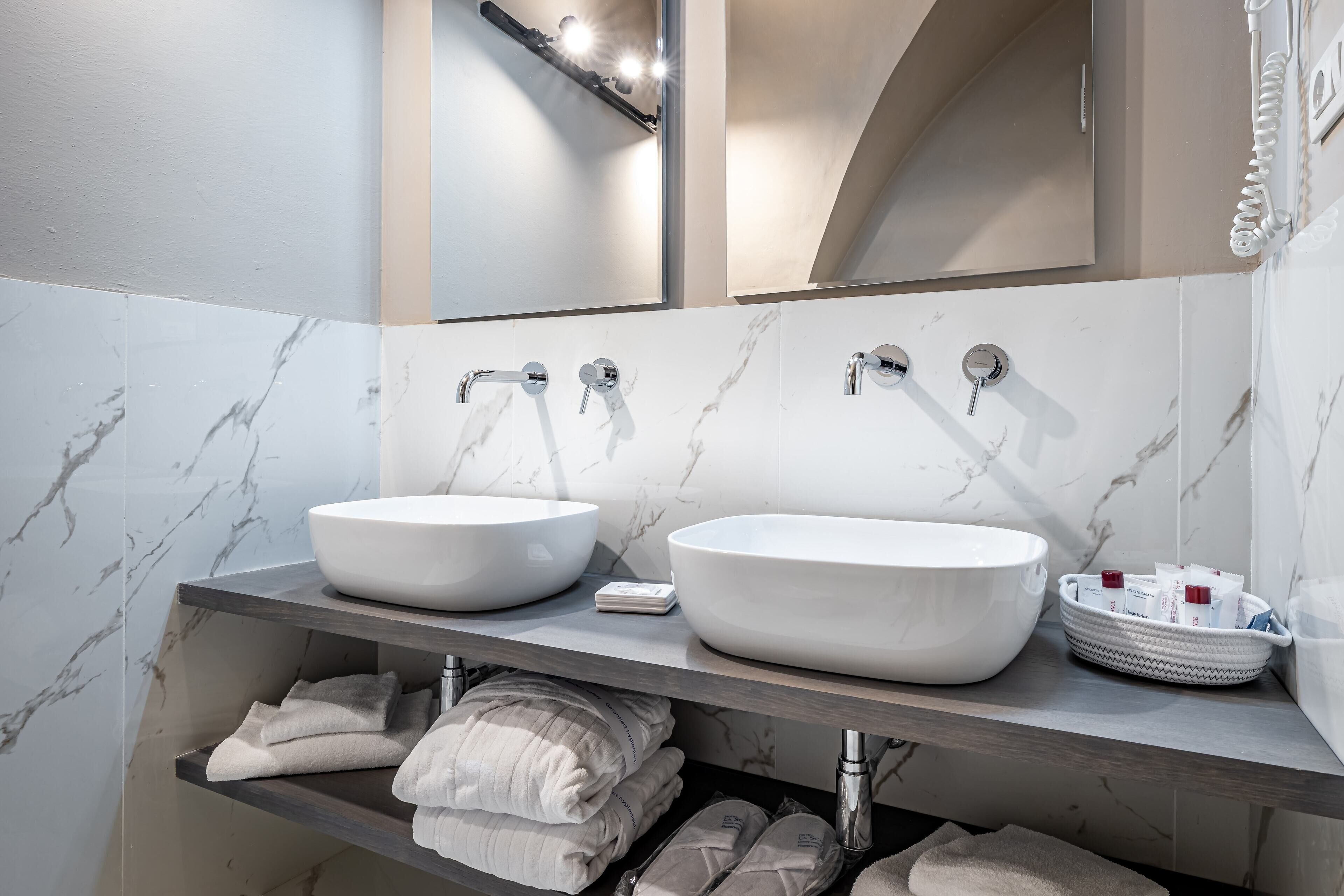 A modern bathroom with two large white sinks, a mirror, and a towel rack.