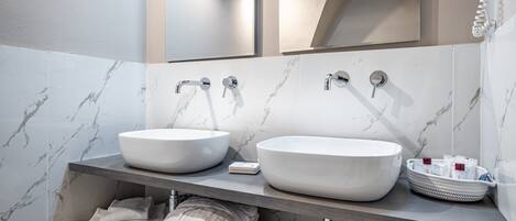 A modern bathroom with two large white sinks, a mirror, and a towel rack.