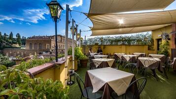 Una terraza exterior con mesas y sillas, un farol y vistas de un edificio histórico.