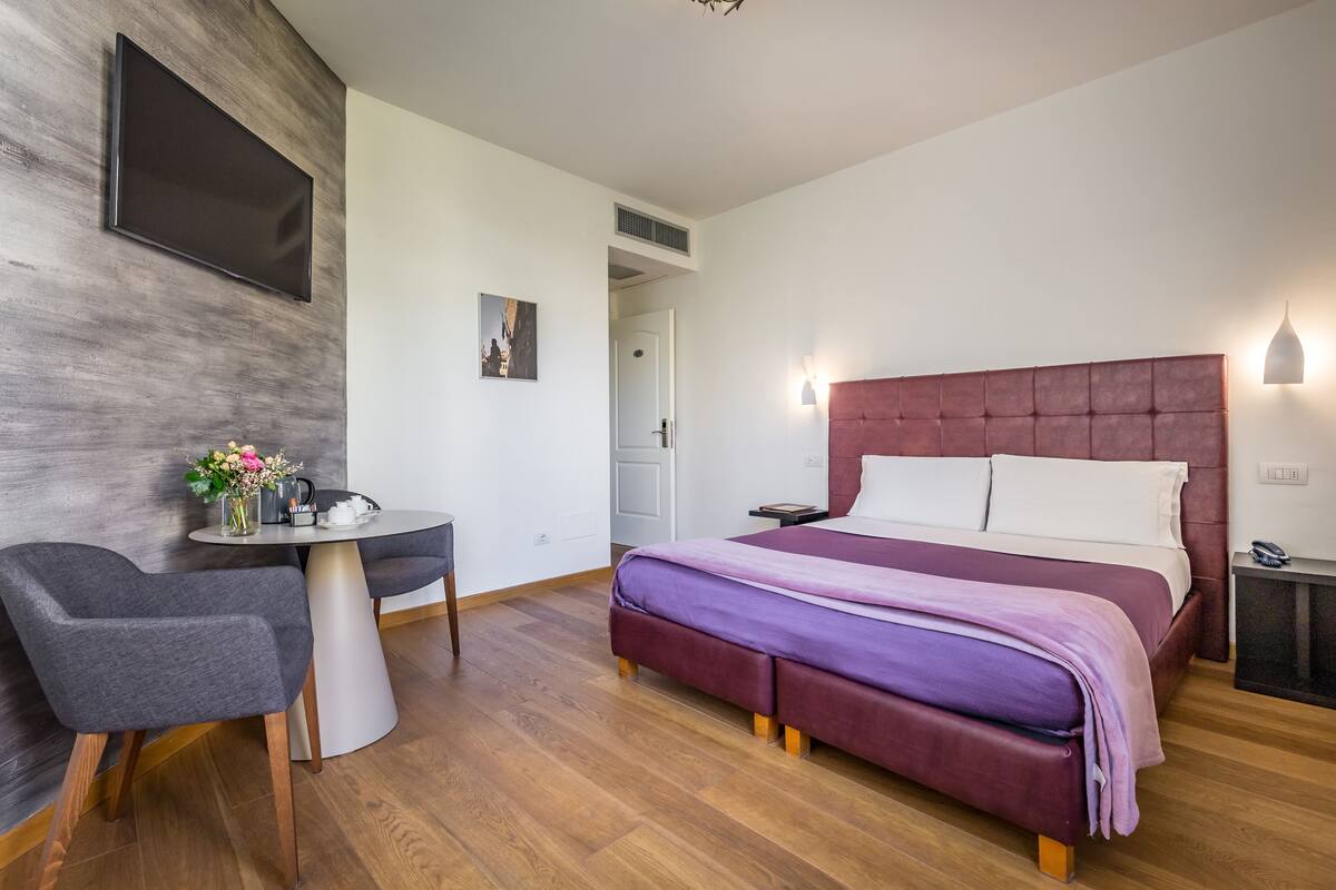 A modern bedroom with a large bed, a desk, and a chair.