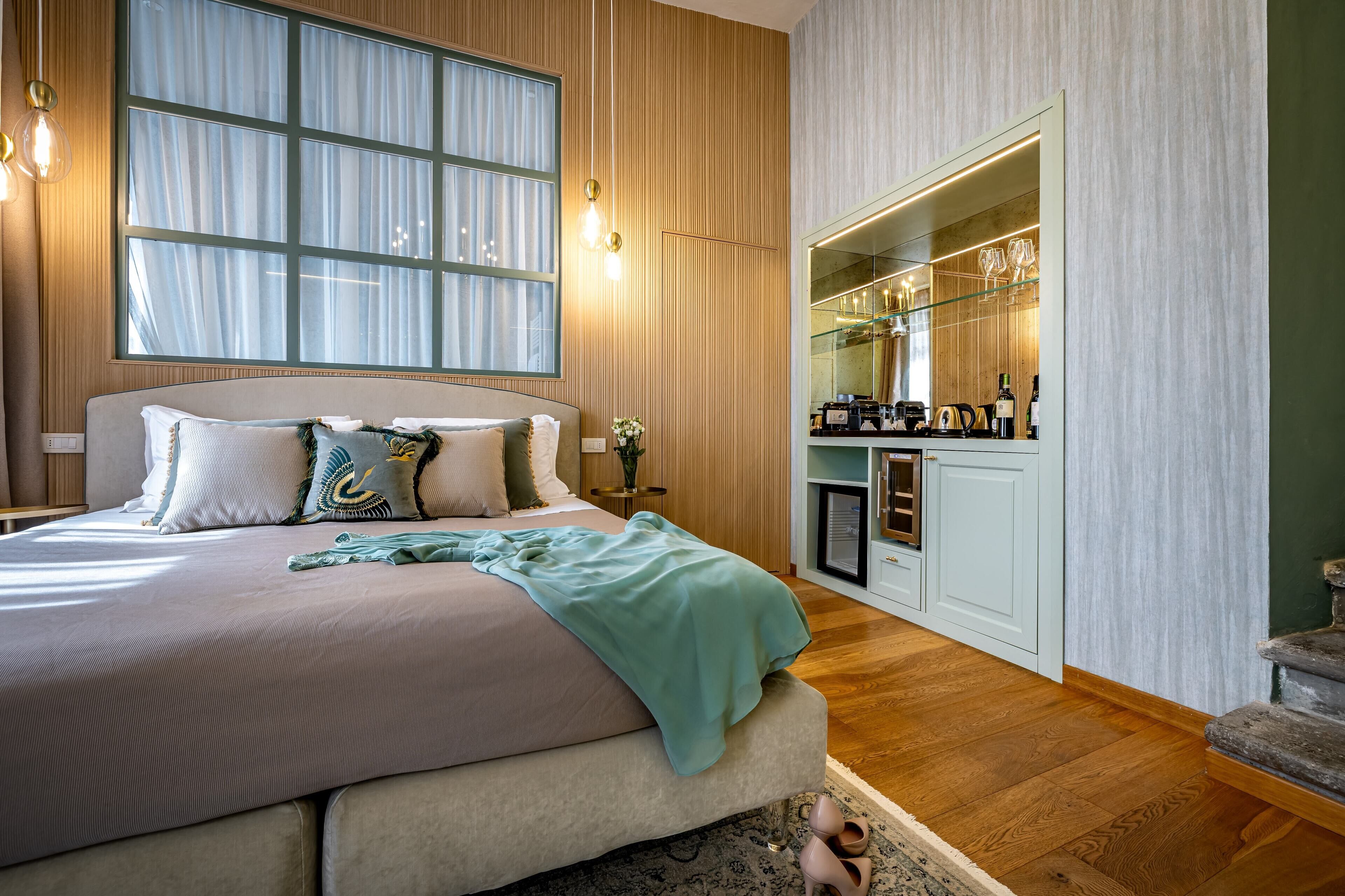 A bedroom with a large bed, a window, and a built-in minibar.