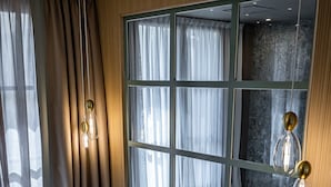 A neatly made bed with multiple pillows, a bedside table with a vase of flowers, and a large window with curtains. - Hotel La Scaletta Al Ponte Vecchio (Florence)