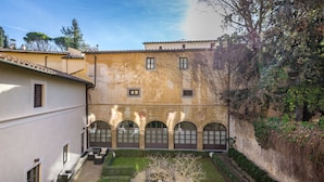 A courtyard with a circular garden, a building with arched windows, and a tree. - Hotel La Scaletta Al Ponte Vecchio (Florence)