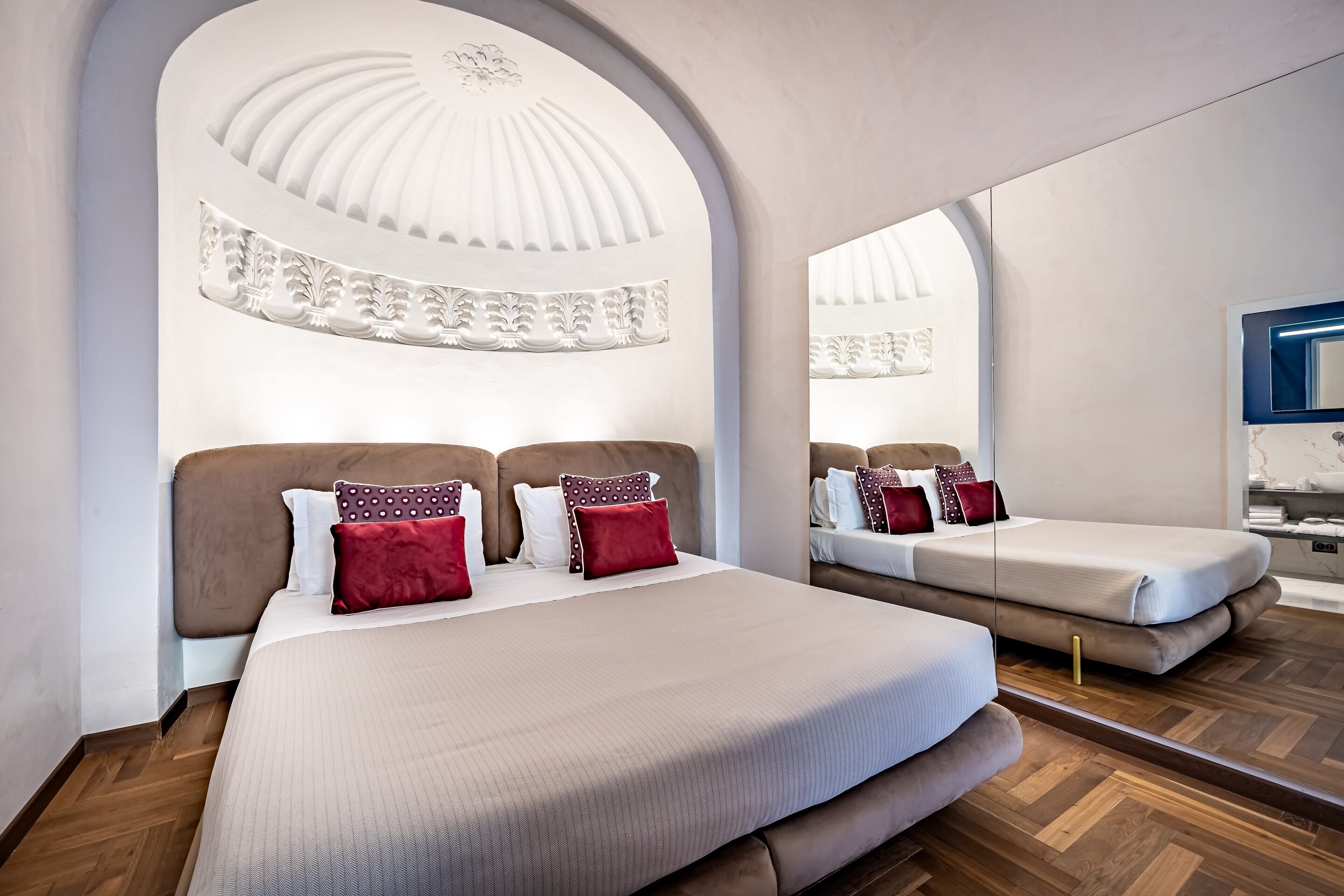 Une chambre d’hôtel moderne avec un grand lit, un miroir et un plancher en bois.