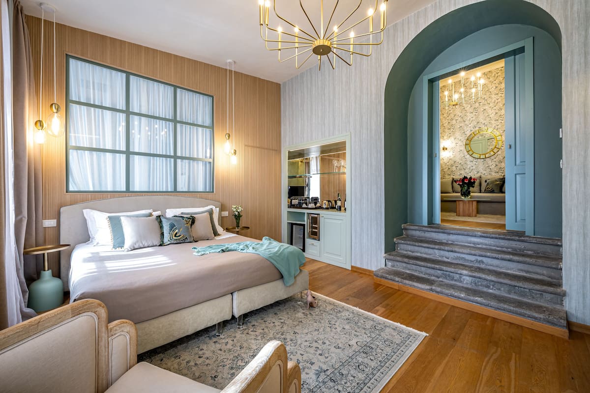A bedroom with a large bed, bedside tables, a dresser, and a vanity with a mirror.