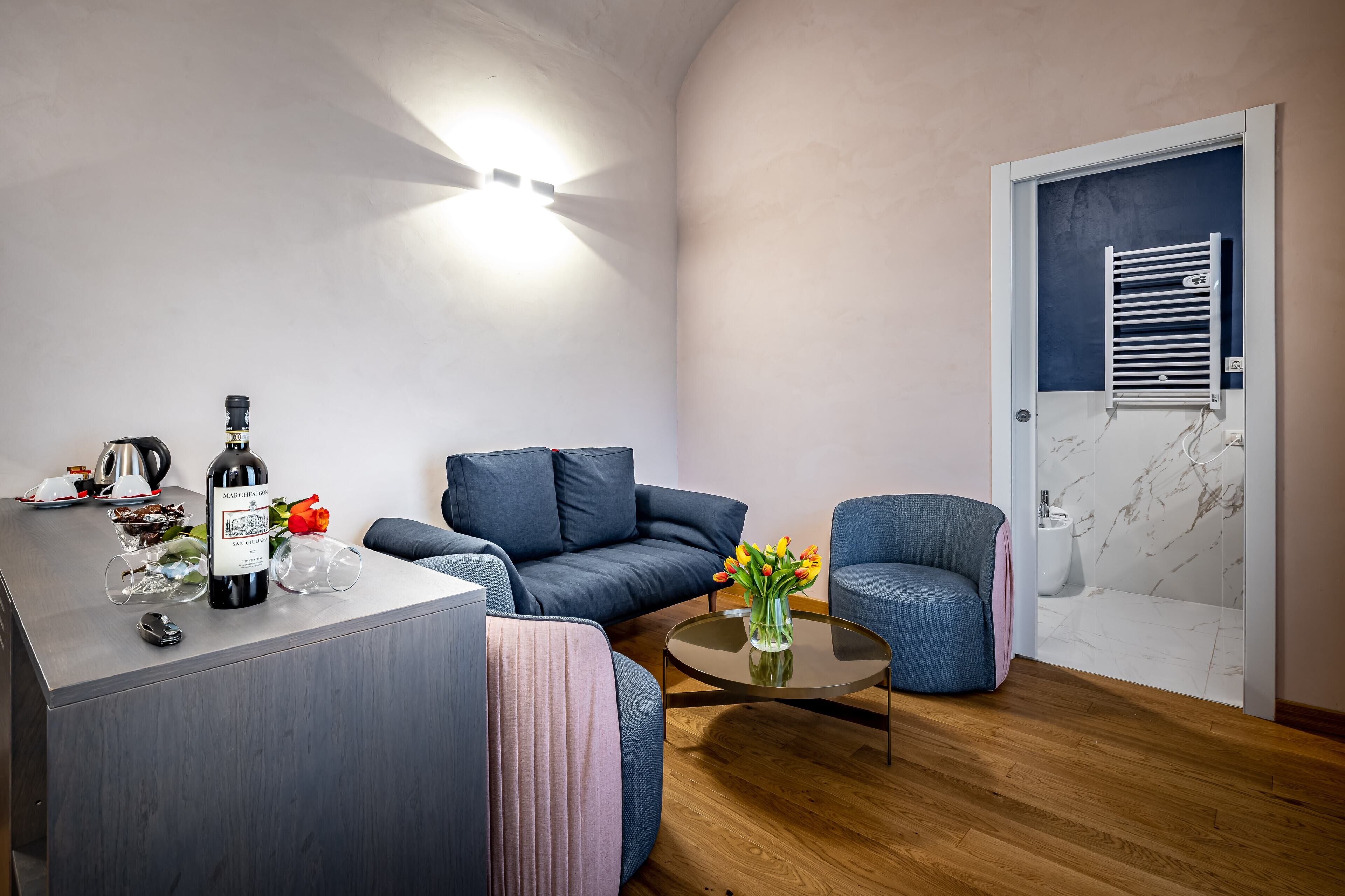 A modern living room with a sofa, a coffee table, and a wine bottle on a counter.