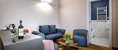 A modern living room with a sofa, a coffee table, and a wine bottle on a counter.